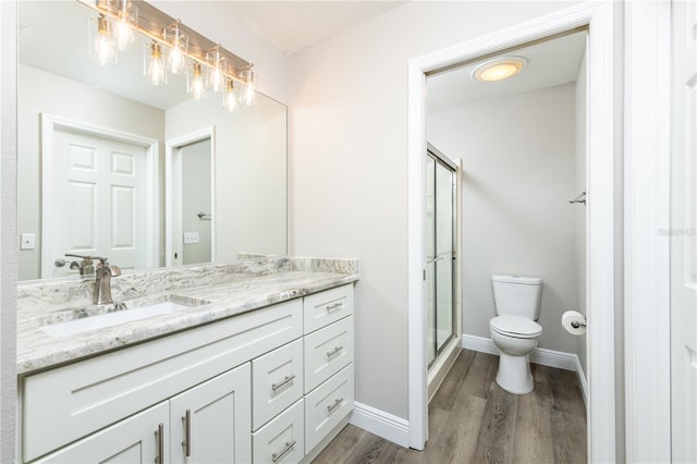 bathroom featuring toilet, hardwood / wood-style floors, walk in shower, and vanity