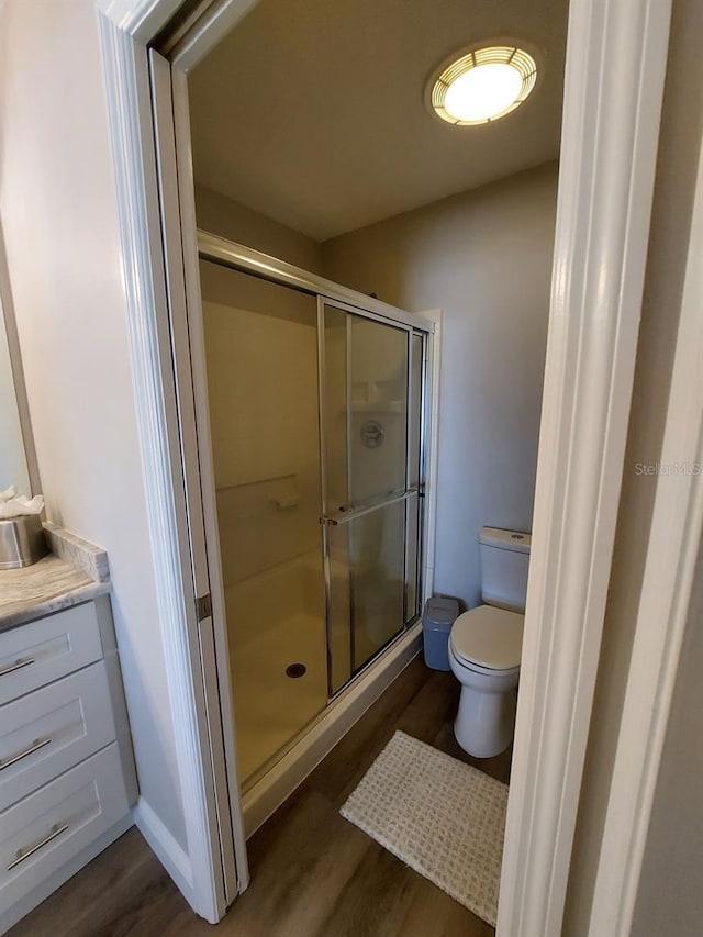 bathroom featuring toilet, an enclosed shower, hardwood / wood-style flooring, and vanity