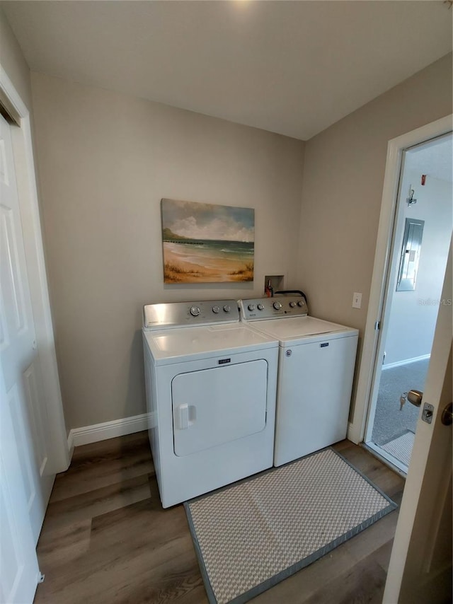 clothes washing area with washer and clothes dryer and light wood-type flooring