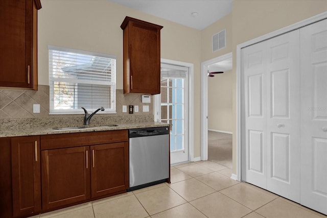 kitchen featuring decorative backsplash, light tile patterned floors, light stone countertops, stainless steel dishwasher, and sink