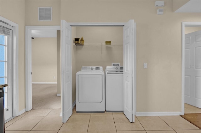 laundry area featuring washing machine and clothes dryer and light tile patterned floors