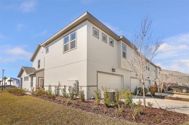 view of side of property featuring a yard, cooling unit, and a garage