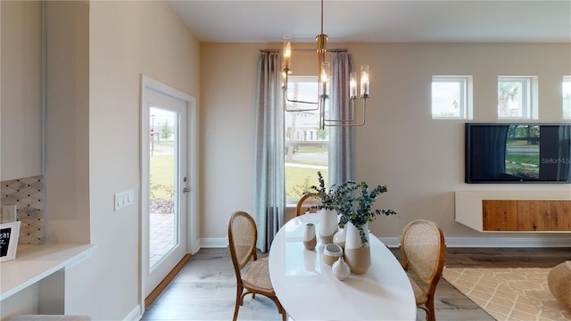 dining area with a healthy amount of sunlight, a chandelier, and light hardwood / wood-style floors