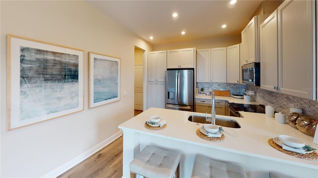 kitchen featuring light wood-type flooring, a kitchen breakfast bar, sink, stainless steel appliances, and kitchen peninsula