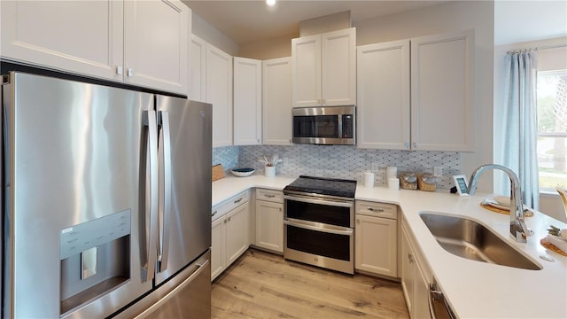 kitchen featuring white cabinets, appliances with stainless steel finishes, light wood-type flooring, and sink