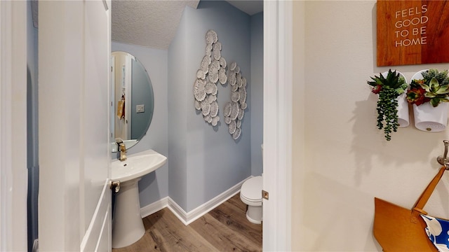 bathroom featuring wood-type flooring, a textured ceiling, and toilet