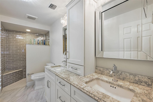 bathroom with vanity, toilet, and tiled shower