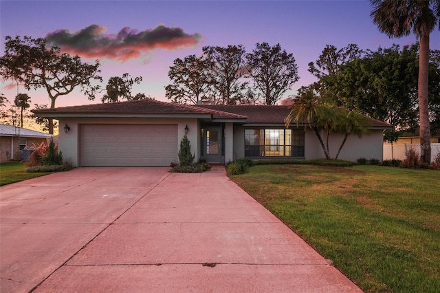 single story home featuring a garage and a yard