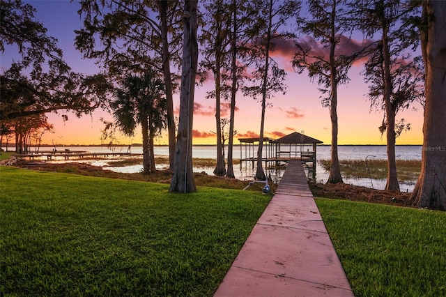 view of dock with a lawn and a water view