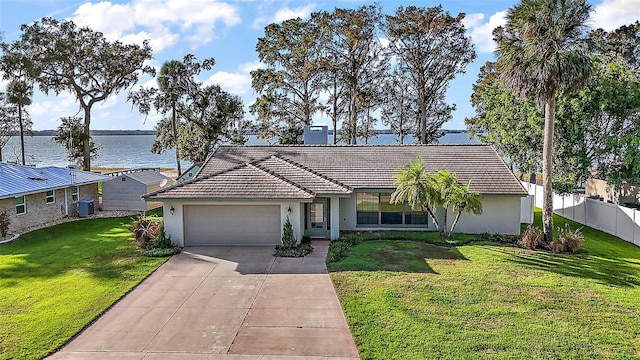 single story home with a front lawn, a water view, and a garage