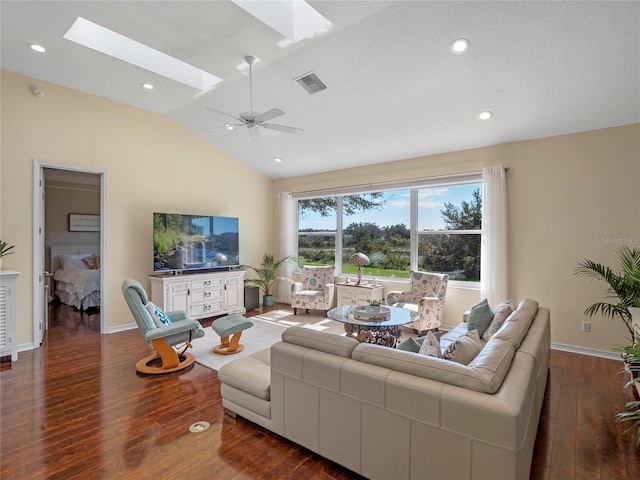 living room with lofted ceiling with skylight, dark wood-type flooring, and ceiling fan