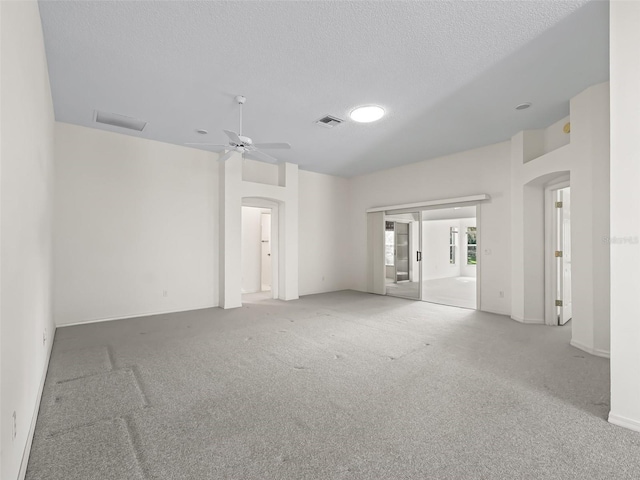 carpeted spare room featuring ceiling fan and a textured ceiling