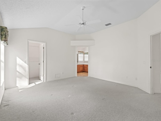 carpeted spare room with ceiling fan, vaulted ceiling, and a textured ceiling