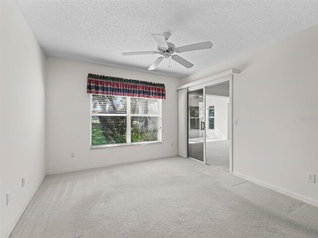 carpeted empty room featuring a textured ceiling and ceiling fan