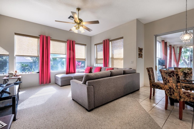 living room with plenty of natural light, light tile patterned floors, and ceiling fan with notable chandelier