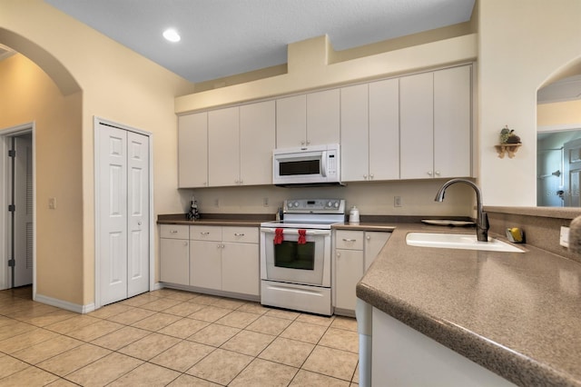 kitchen featuring light tile patterned flooring, white appliances, white cabinetry, and sink