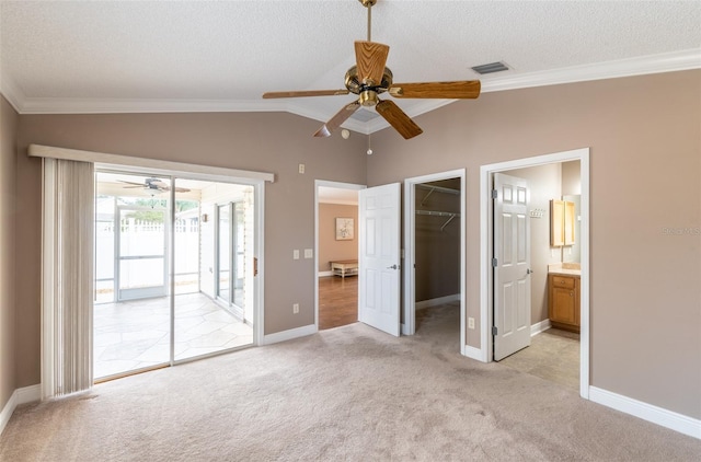 unfurnished bedroom with a walk in closet, access to exterior, a closet, light carpet, and ceiling fan