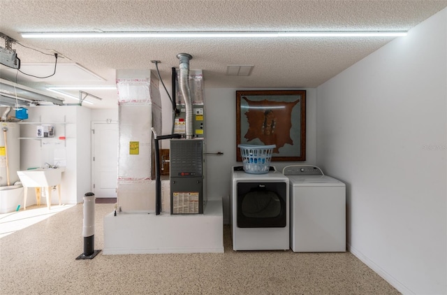 laundry room featuring a textured ceiling, sink, separate washer and dryer, and gas water heater