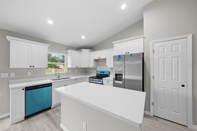 kitchen with lofted ceiling, a kitchen island, stainless steel appliances, sink, and white cabinetry