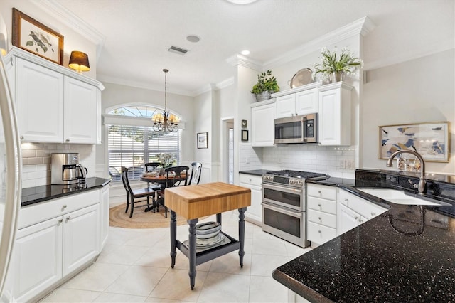 kitchen featuring hanging light fixtures, appliances with stainless steel finishes, white cabinetry, ornamental molding, and sink