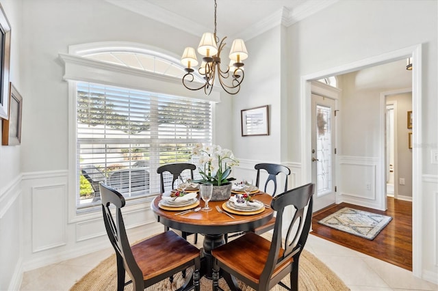 dining space featuring an inviting chandelier, ornamental molding, and light wood-type flooring