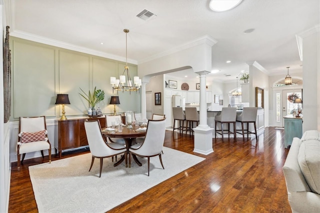 dining space with a notable chandelier, crown molding, ornate columns, and dark hardwood / wood-style floors