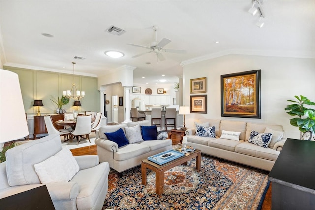 living room featuring ornamental molding, vaulted ceiling, and ceiling fan with notable chandelier