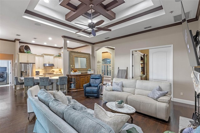 living room featuring dark hardwood / wood-style flooring, washer / dryer, ornamental molding, and a raised ceiling