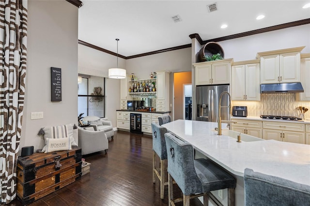 kitchen featuring sink, appliances with stainless steel finishes, hanging light fixtures, cream cabinets, and beverage cooler