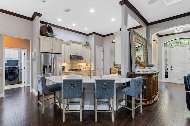 kitchen featuring washer / dryer, a breakfast bar area, backsplash, and appliances with stainless steel finishes