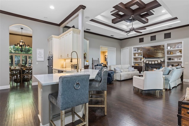 kitchen featuring a stone fireplace, dark hardwood / wood-style flooring, ornamental molding, kitchen peninsula, and built in shelves