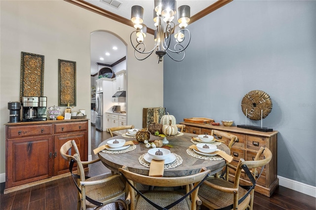 dining space with crown molding, dark wood-type flooring, and an inviting chandelier