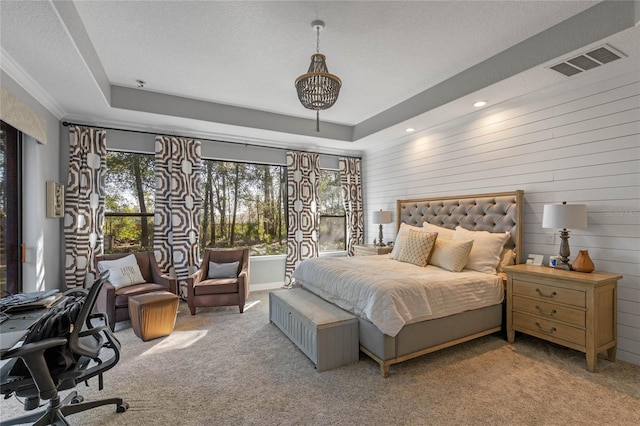 bedroom featuring wooden walls, light colored carpet, a textured ceiling, and a tray ceiling