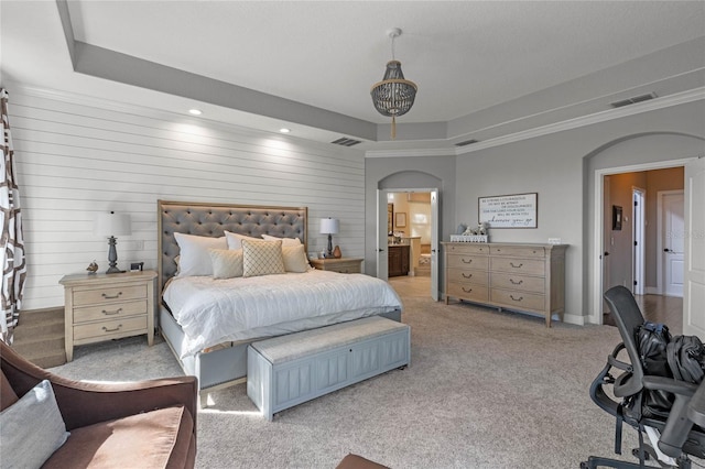 carpeted bedroom with ornamental molding, a tray ceiling, and wood walls