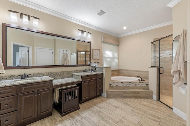 bathroom with independent shower and bath, ornamental molding, vanity, and a textured ceiling