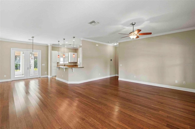 unfurnished living room featuring dark wood-type flooring, ceiling fan, and ornamental molding