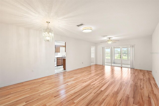 unfurnished living room with light hardwood / wood-style flooring and ceiling fan with notable chandelier