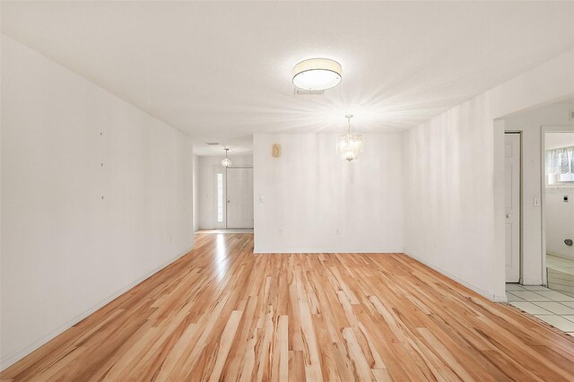 spare room featuring light hardwood / wood-style flooring and a notable chandelier