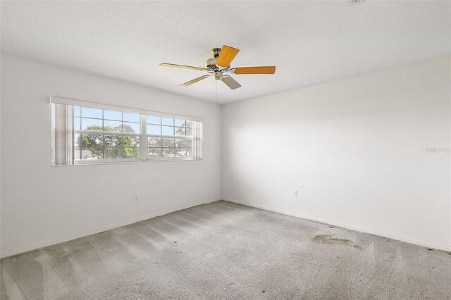 empty room with ceiling fan, carpet, and a textured ceiling