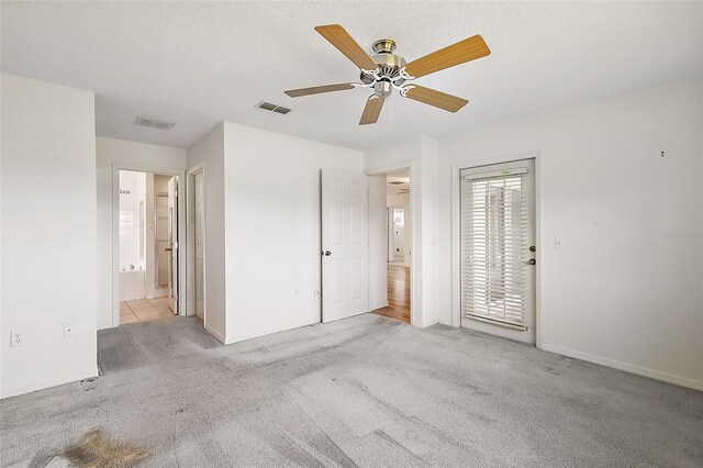 unfurnished bedroom featuring ensuite bath, light carpet, and ceiling fan