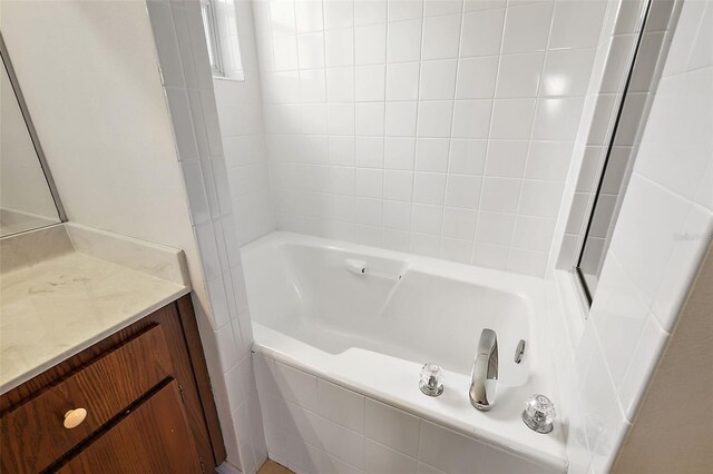 bathroom with vanity and tiled bath