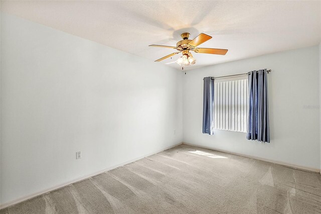 unfurnished room with ceiling fan and carpet