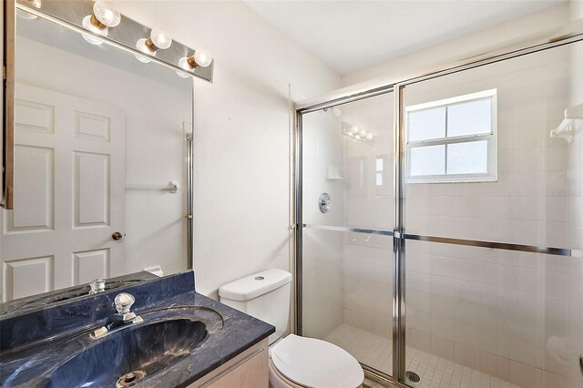 bathroom featuring toilet, an enclosed shower, and vanity