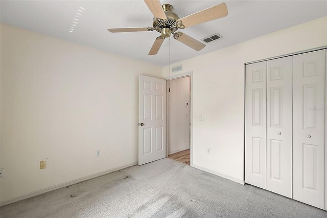 unfurnished bedroom featuring light carpet, a closet, and ceiling fan