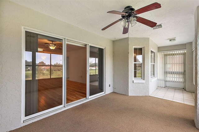 unfurnished sunroom featuring ceiling fan