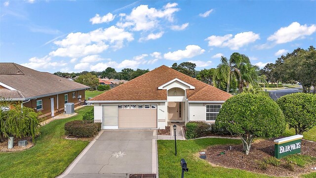 single story home featuring cooling unit, a front lawn, and a garage