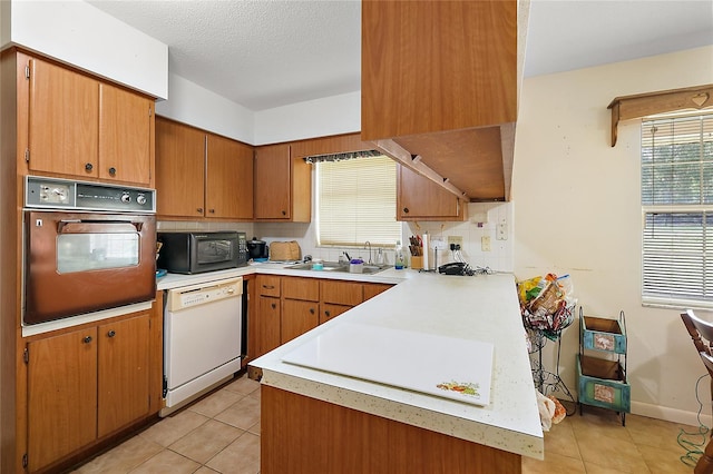 kitchen featuring a textured ceiling, black appliances, sink, and light tile patterned floors