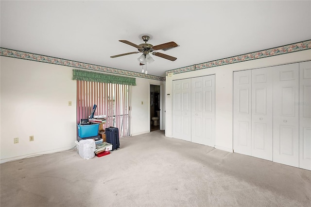 unfurnished bedroom featuring ceiling fan, carpet flooring, and two closets