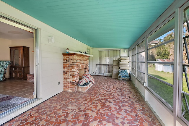 unfurnished sunroom featuring lofted ceiling, a brick fireplace, and wood ceiling