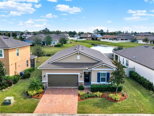 view of front of property with a front yard, a garage, and a water view